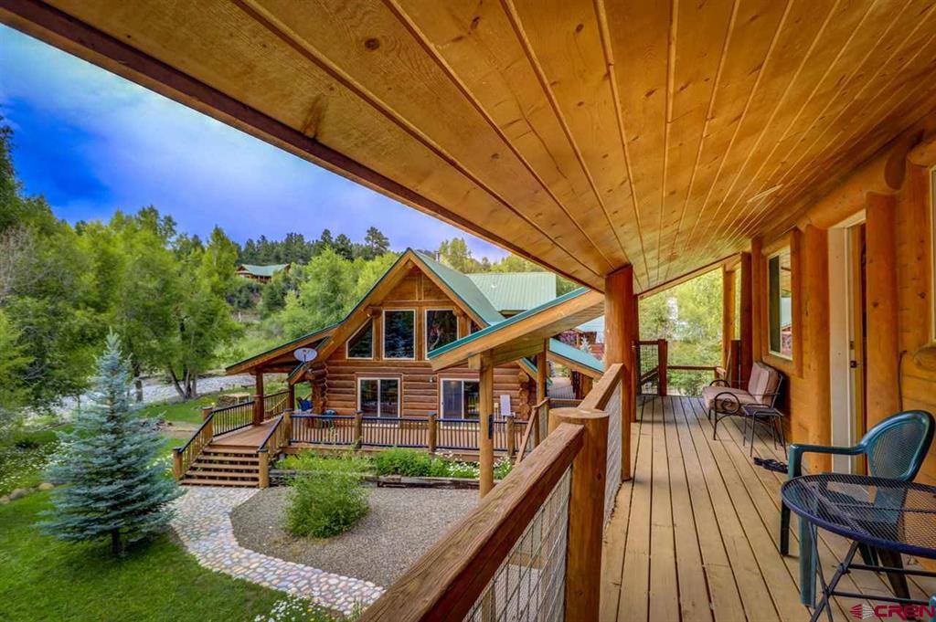 A log cabin with a deck overlooking a wooded area.