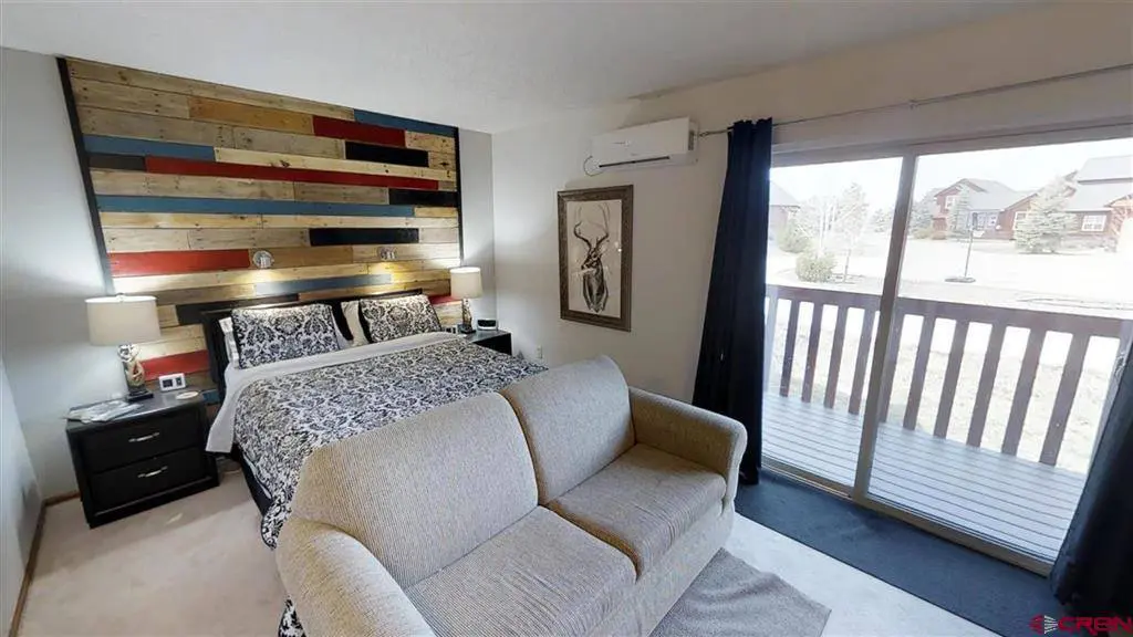 A bedroom with a couch and a sliding glass door.