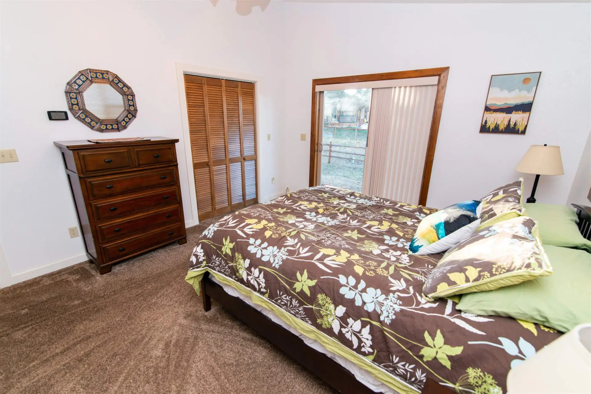 A bedroom with a bed, dresser, and sliding glass doors.