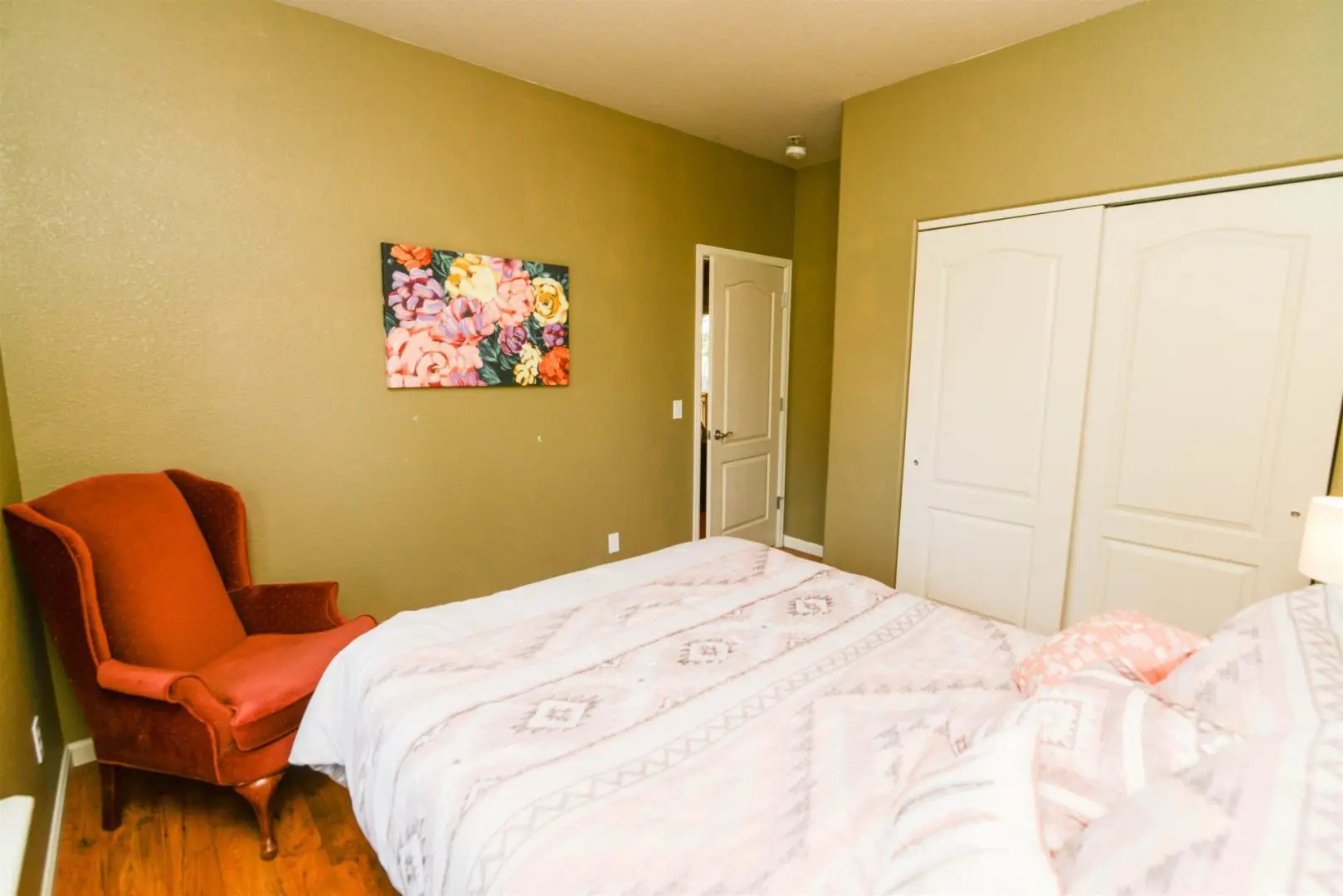 A bedroom with green walls and a pink chair.