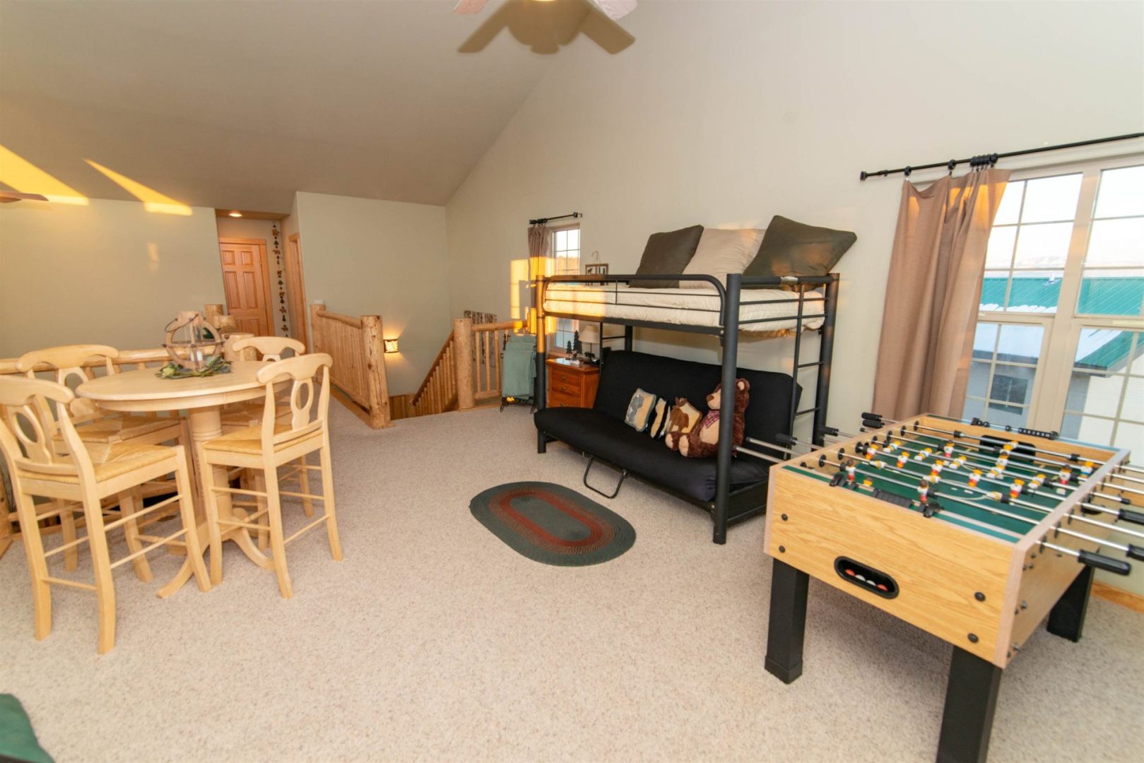 A living room with a foosball table and a futon.