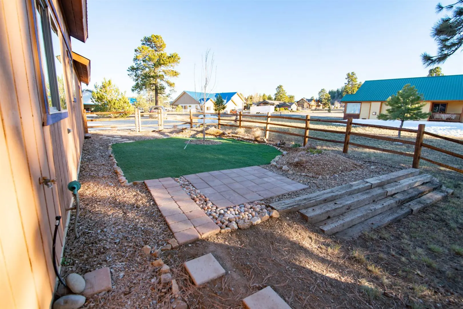 A backyard with a grassy area and a wooden fence.