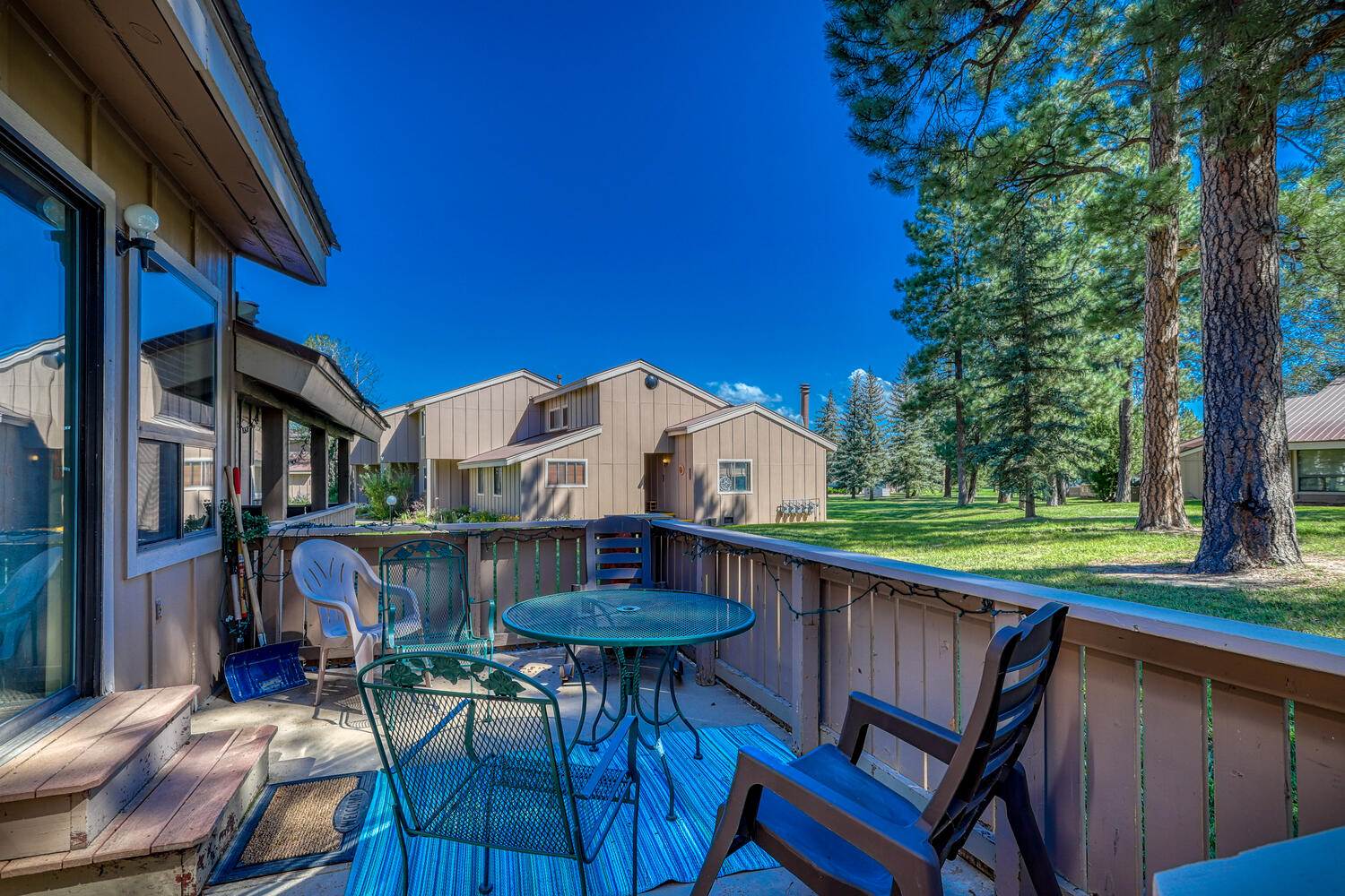 A deck with a table and chairs overlooking a wooded area.