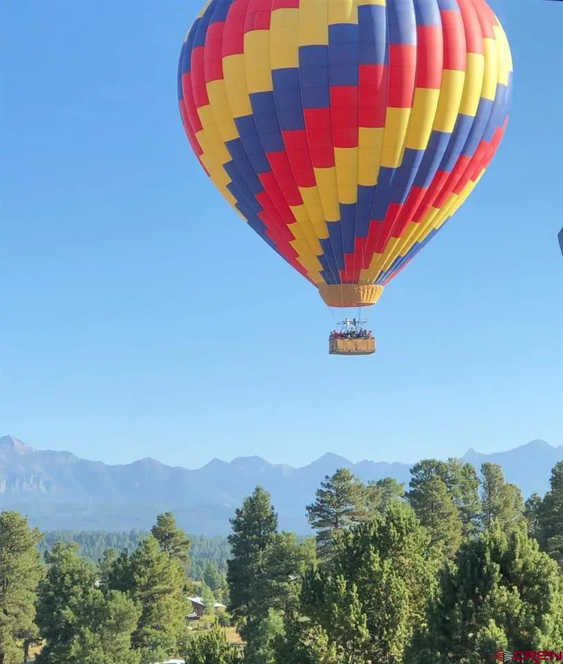 A colorful hot air balloon flying over a forest.