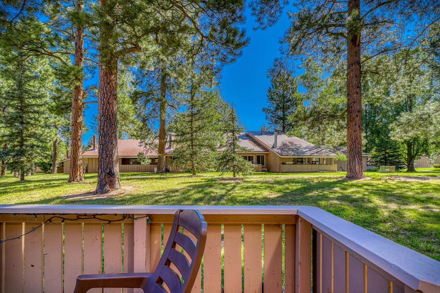 A deck with a chair overlooking a wooded area.