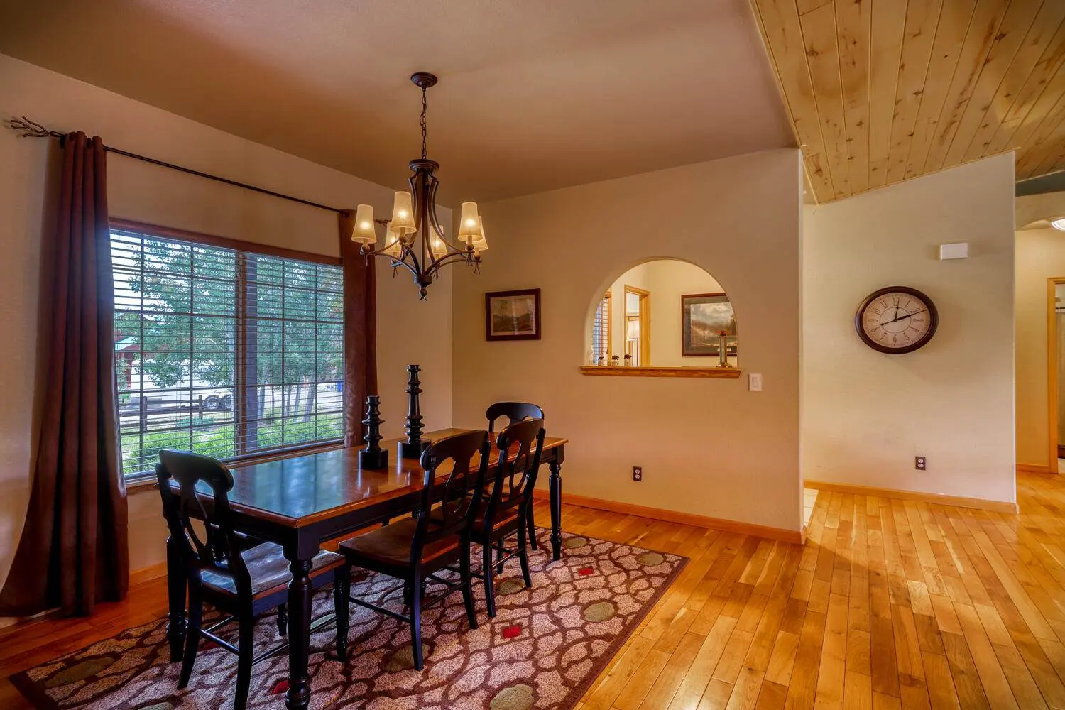 A dining room with hardwood floors and a clock.