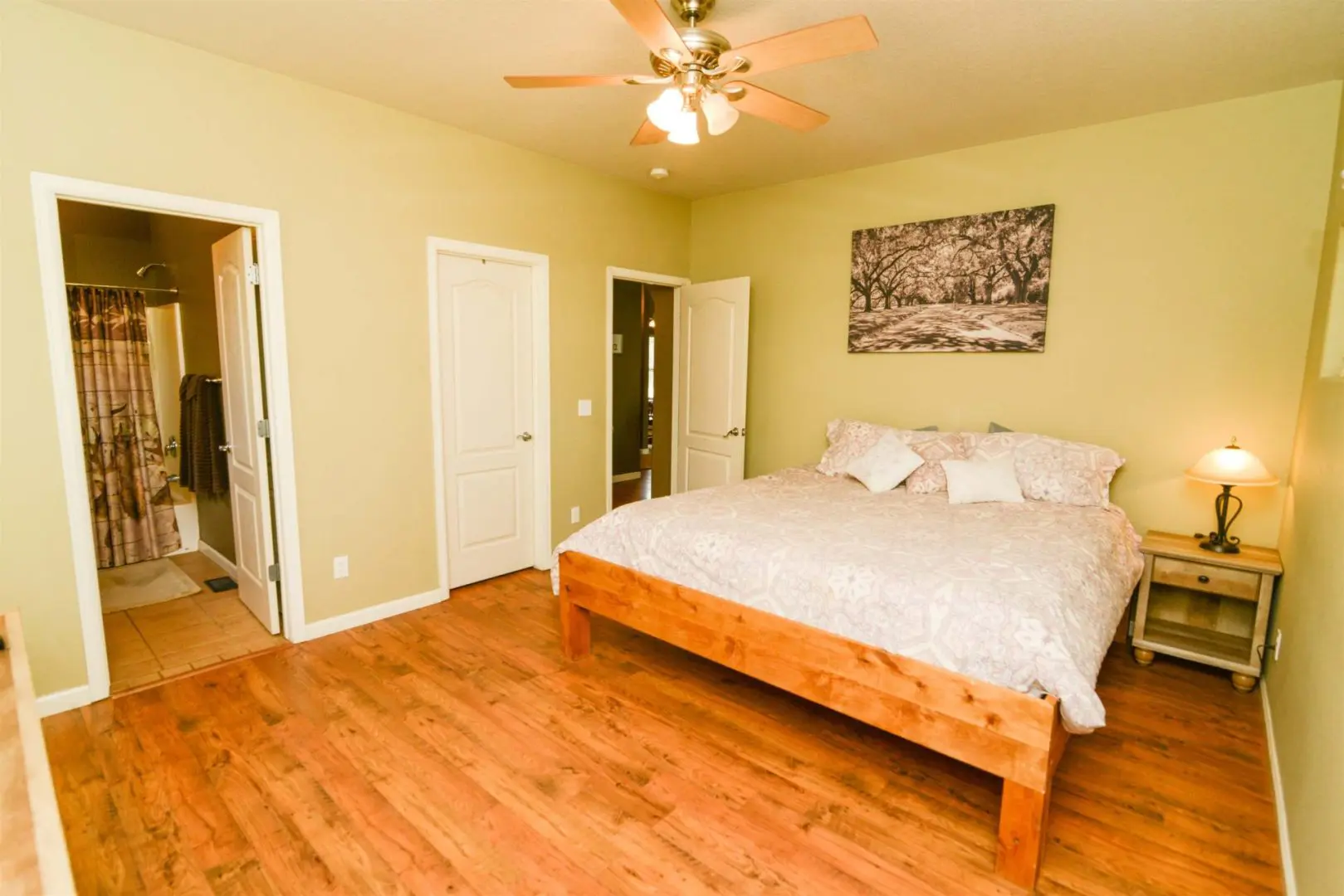 A bedroom with hardwood floors and a ceiling fan.