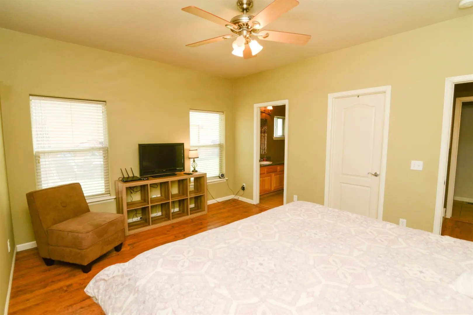 A bedroom with hardwood floors and a ceiling fan.