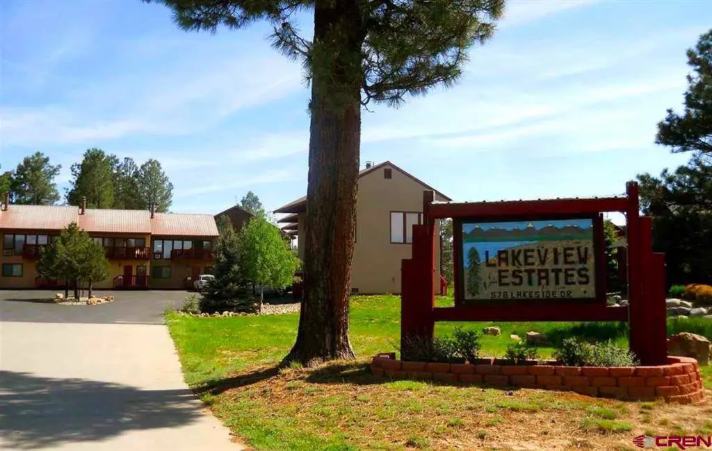 A sign in front of a lodge with trees in the background.