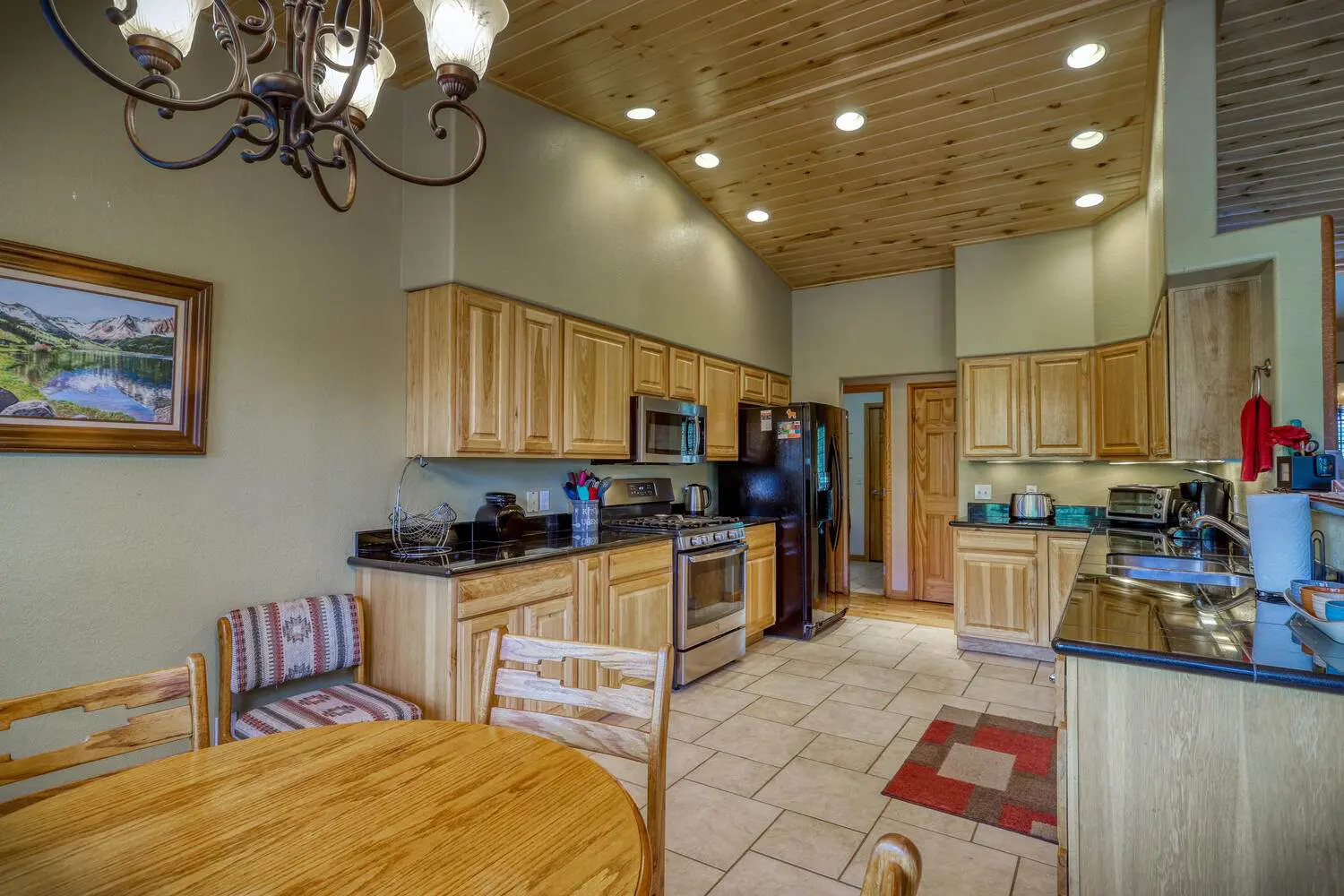 A kitchen with wood cabinets and a table and chairs.