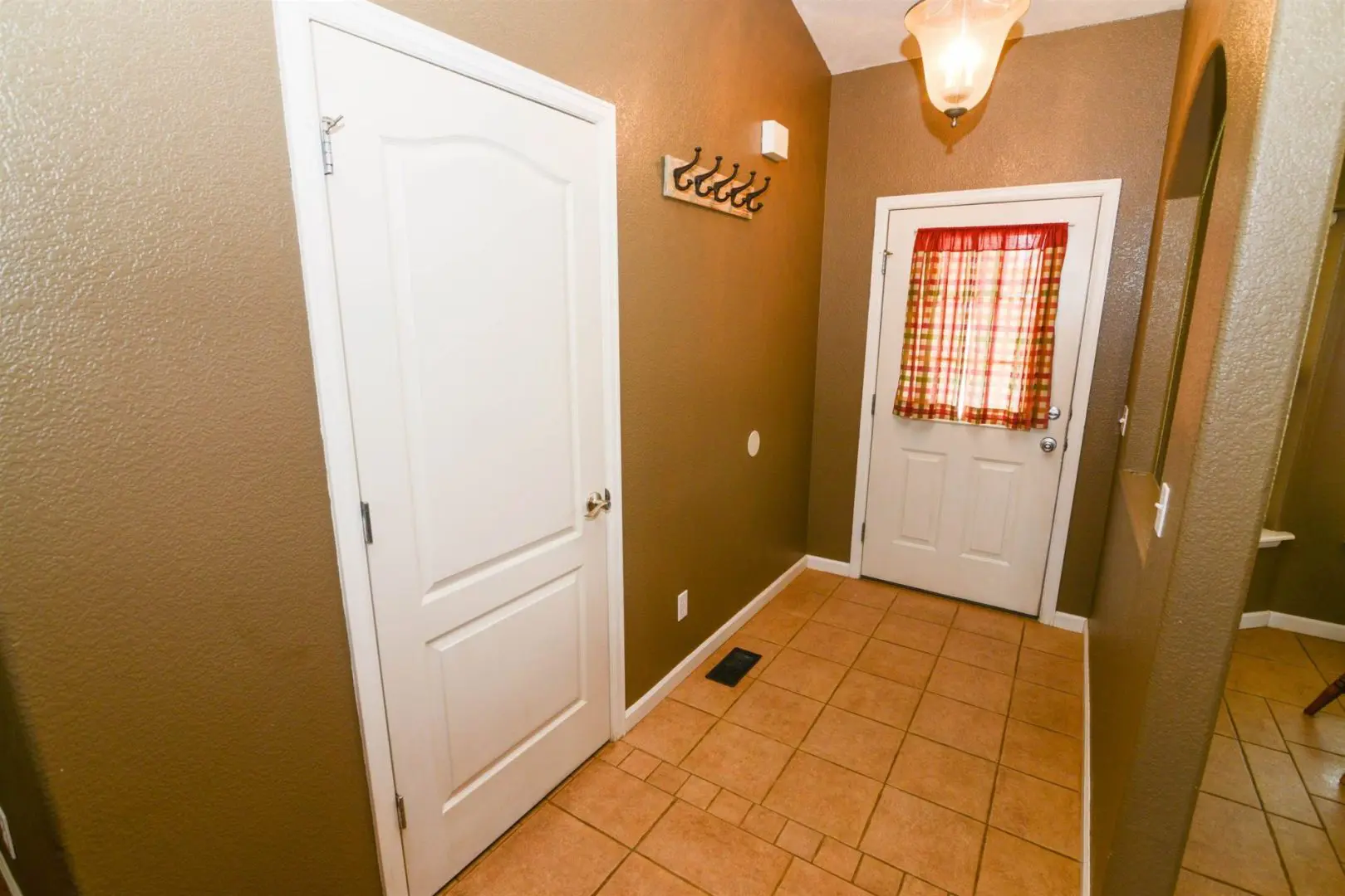 A hallway with two doors and a tiled floor.