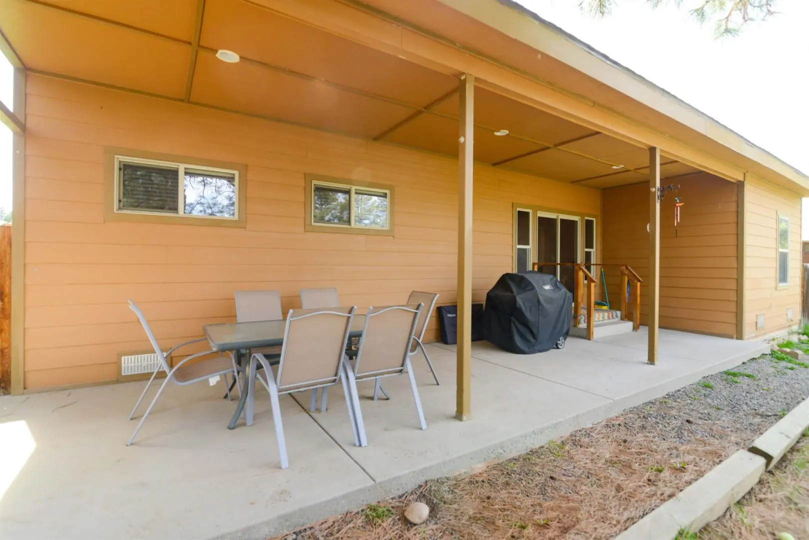 A patio with a table and chairs and a grill.