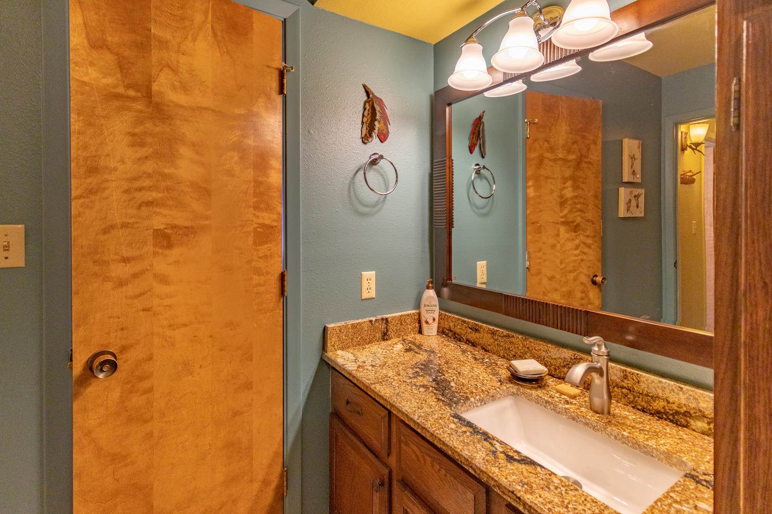 A bathroom with blue walls and a granite counter top.