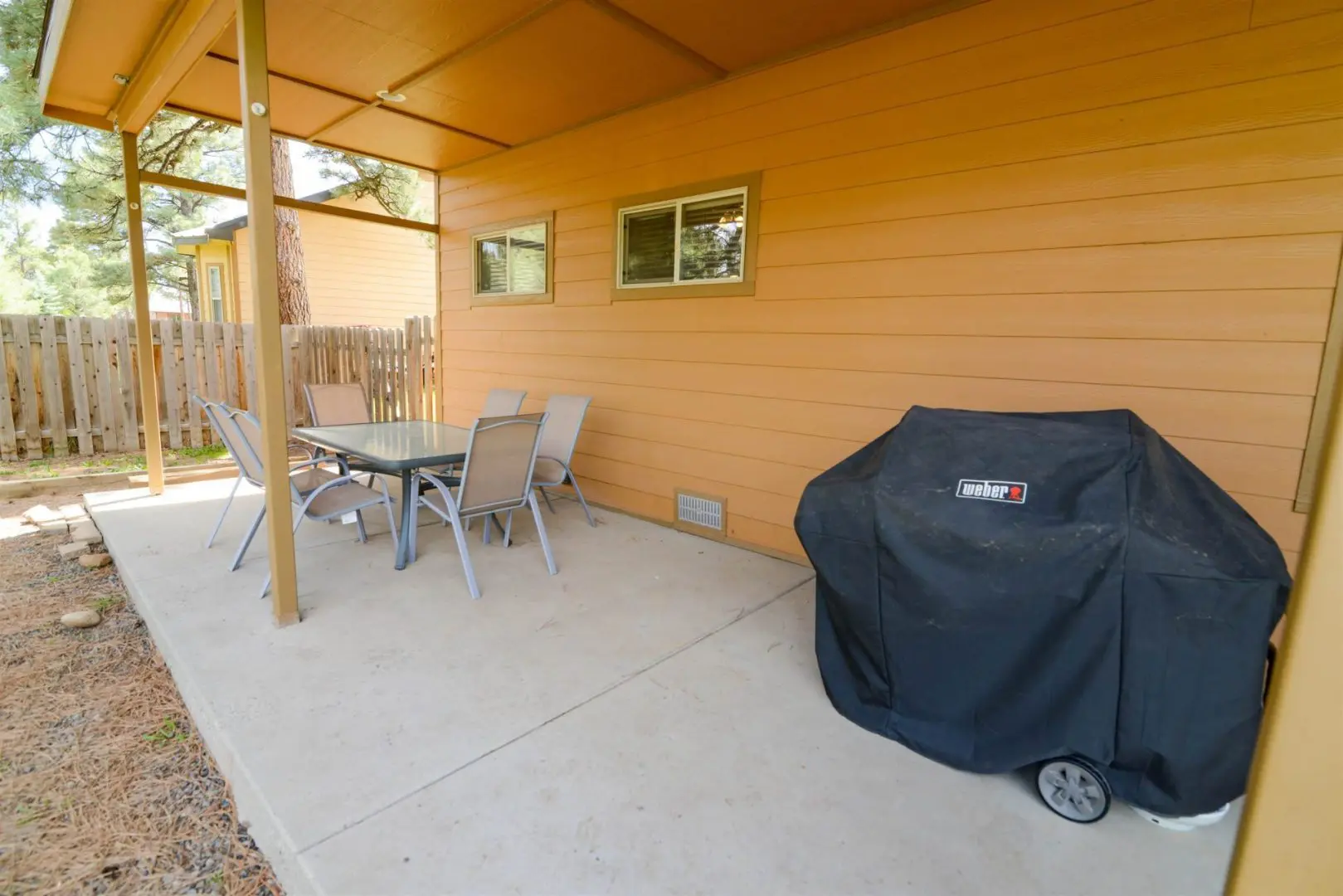 A patio with a table and chairs and a grill.