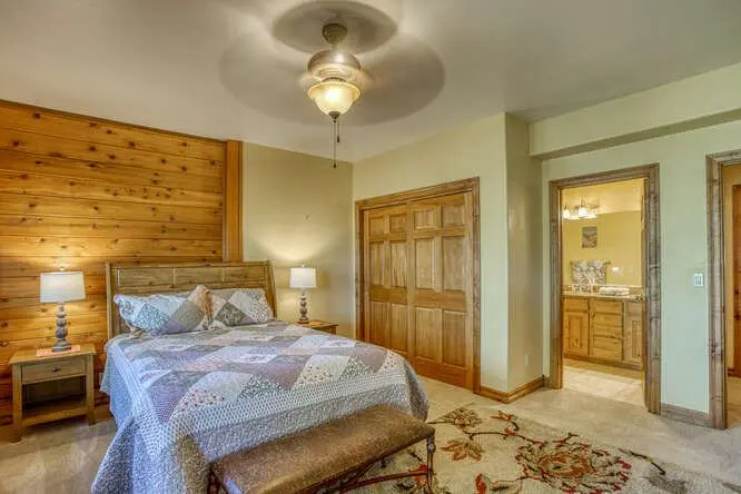 A bedroom in a log cabin with a bed and a ceiling fan.