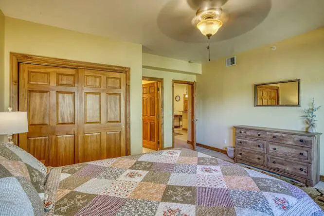 A bedroom with a bed, dresser and ceiling fan.