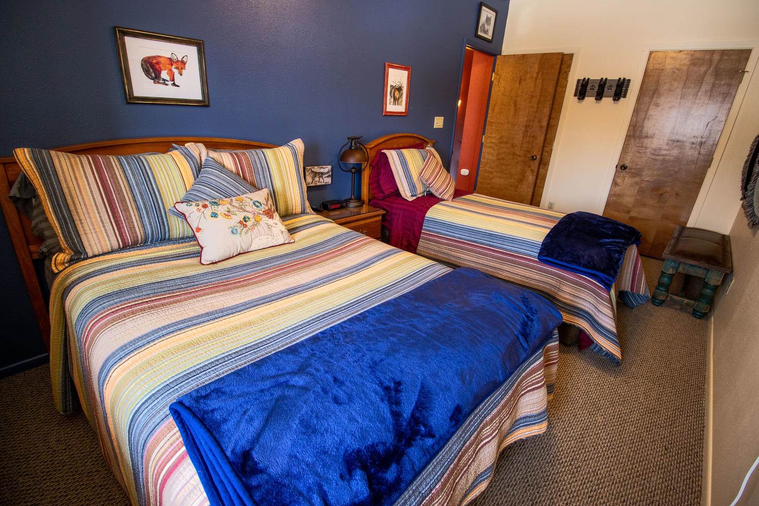 Two beds in a room with blue walls.