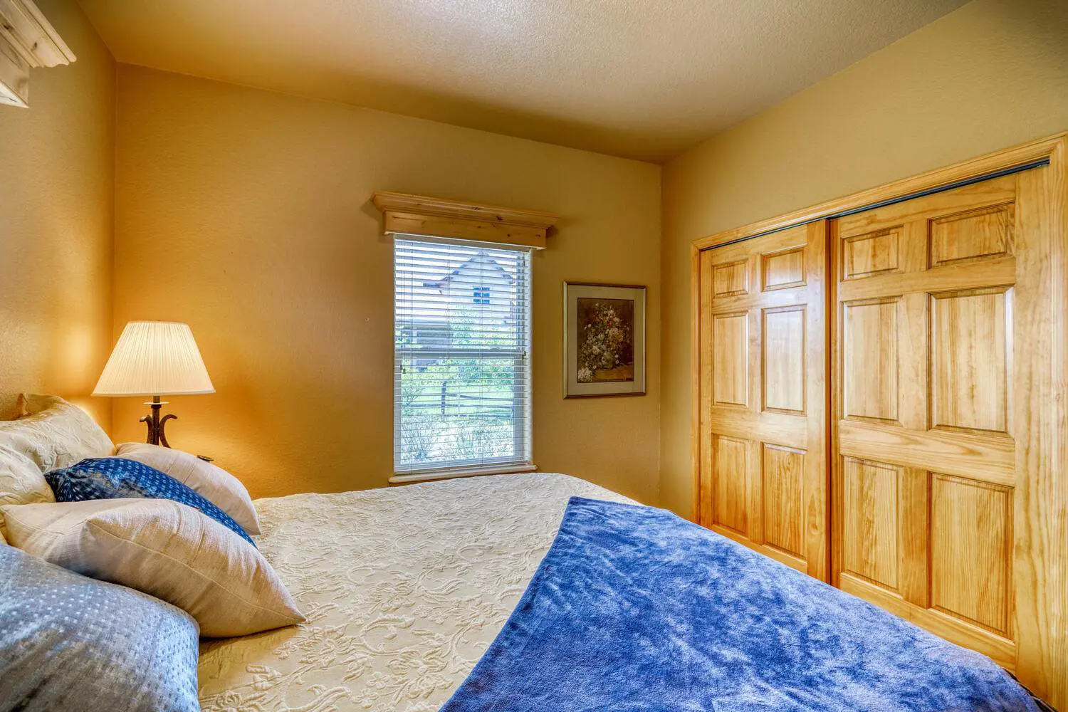 A bedroom with wooden doors and a blue comforter.