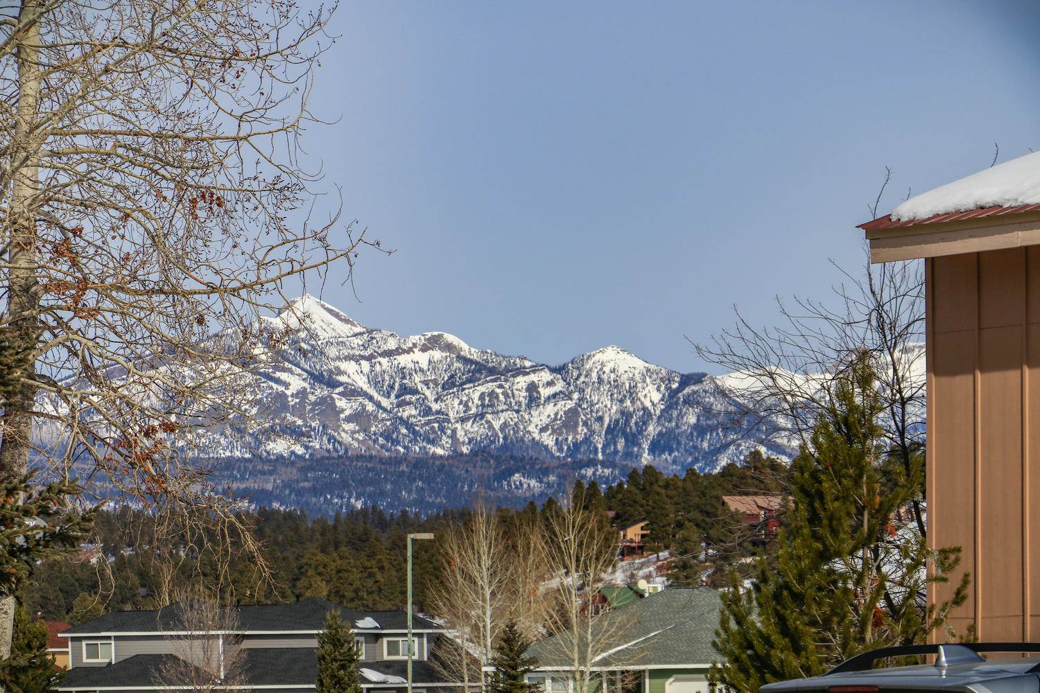 A view of a snow covered mountain range from a house.