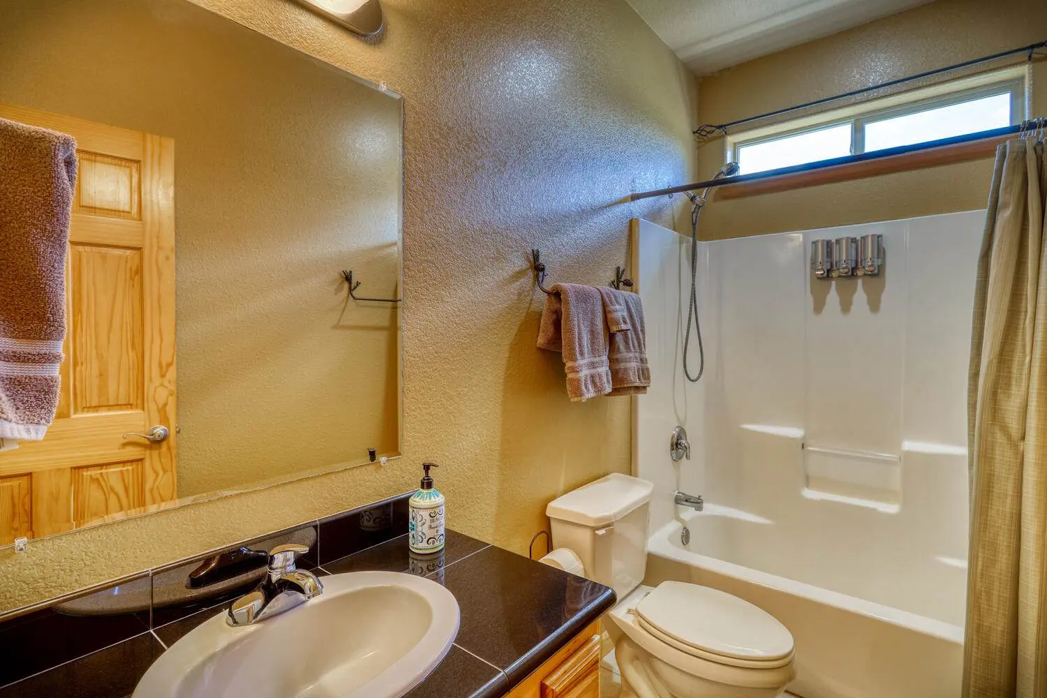 A bathroom with a toilet, shower and sink.