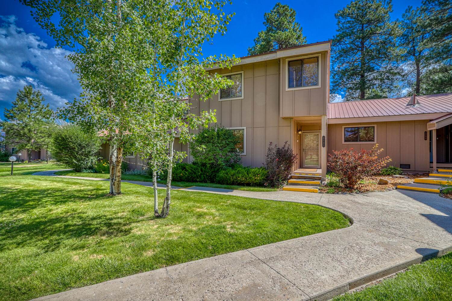 A home with a lawn and trees in front of it.