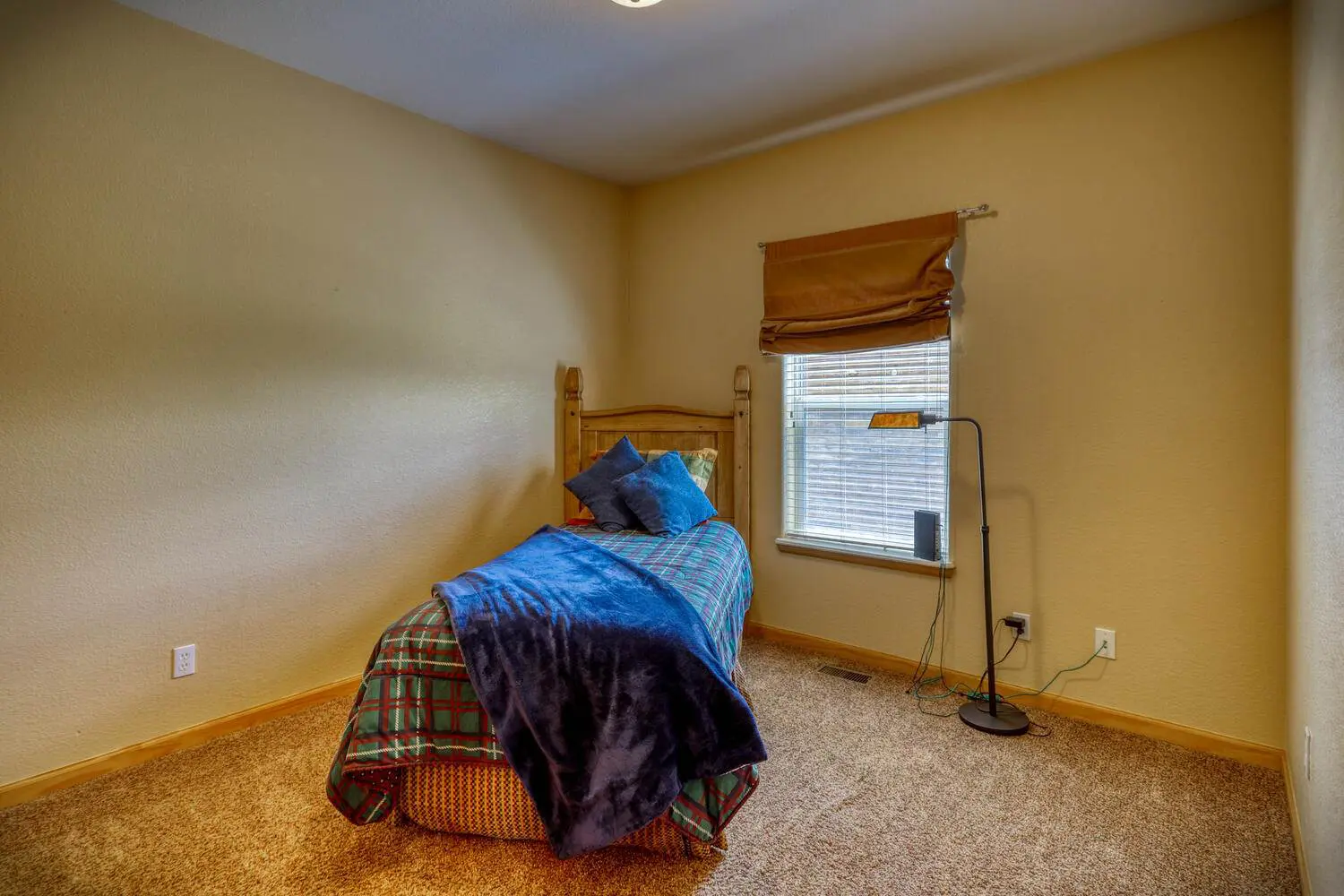 A small bedroom with a bed and a window.