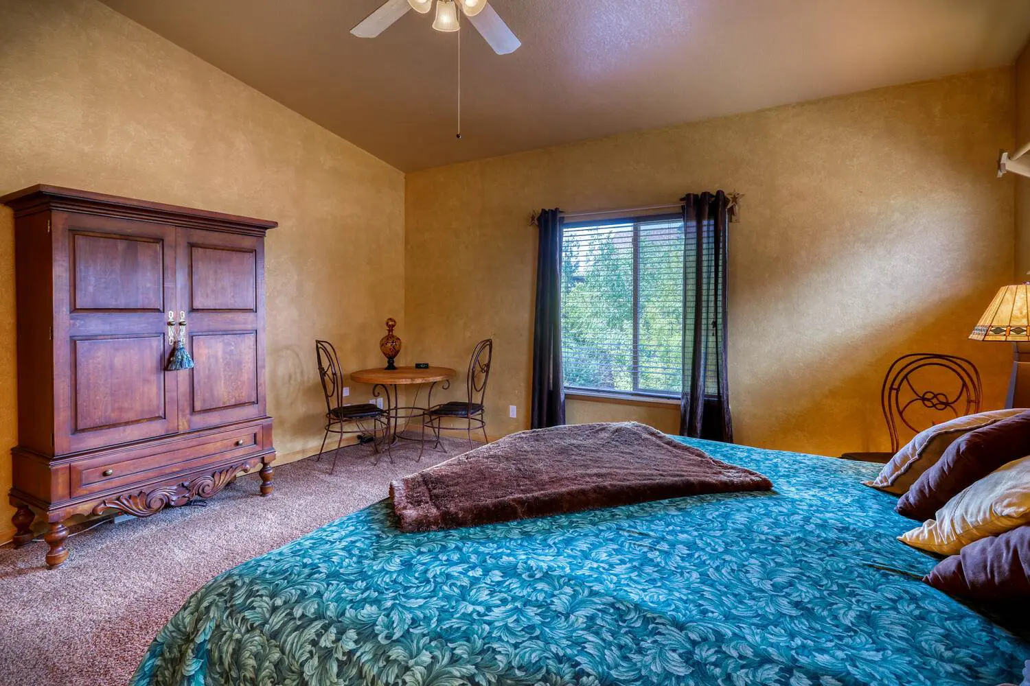 A bedroom with a bed, dresser, and ceiling fan.