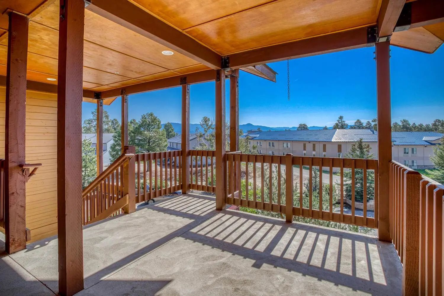 A balcony with wooden railings and a view of the mountains.