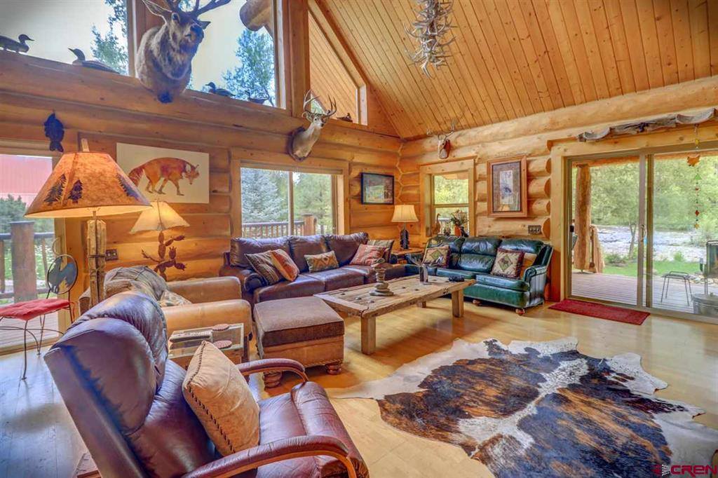 A living room in a log cabin with leather furniture.