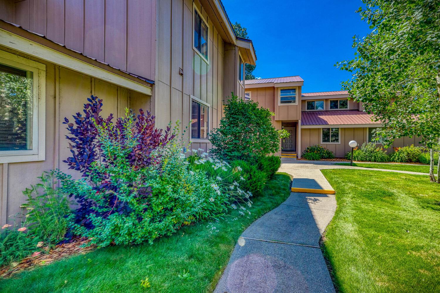 An apartment complex with a walkway and landscaping.