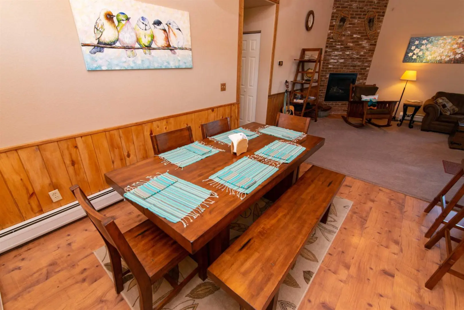 A dining room with wood paneling and a fireplace.