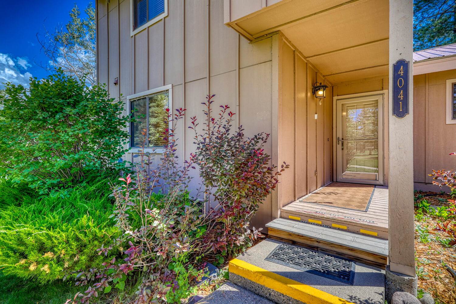 The front door of a home with bushes and trees.