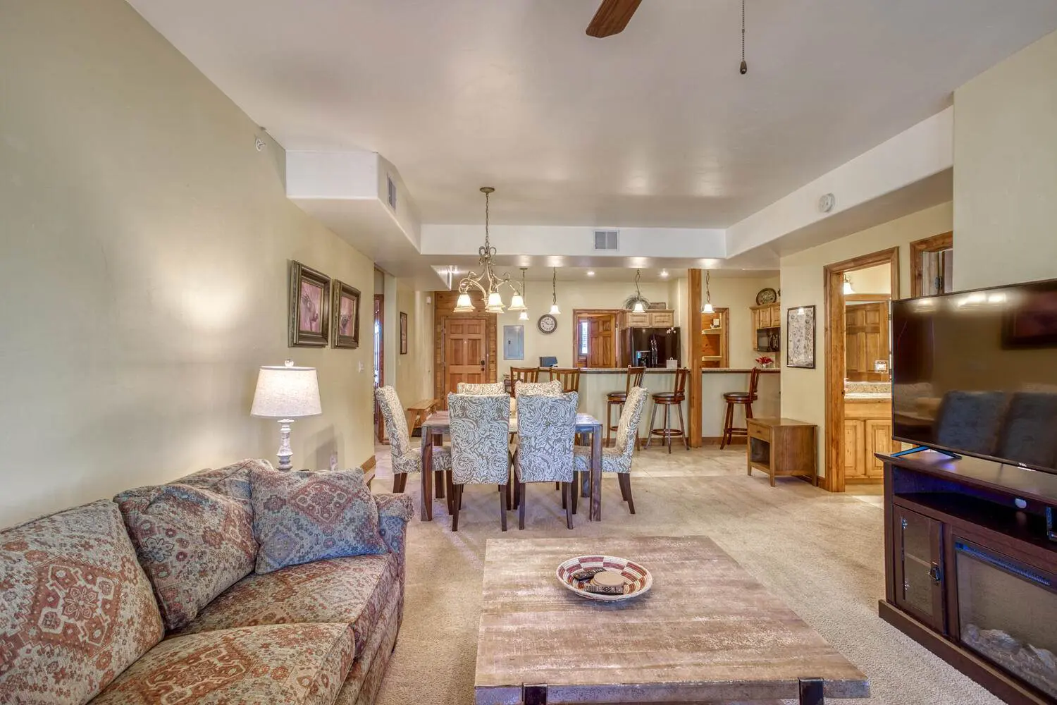 A living room with a flat screen tv and a ceiling fan.