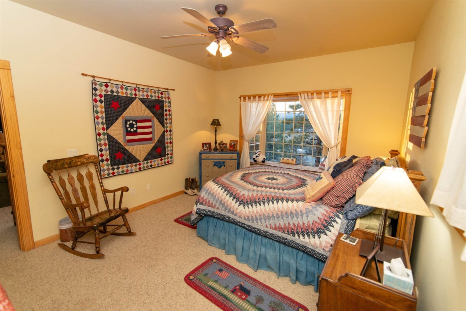 A bedroom with a bed and a rocking chair.