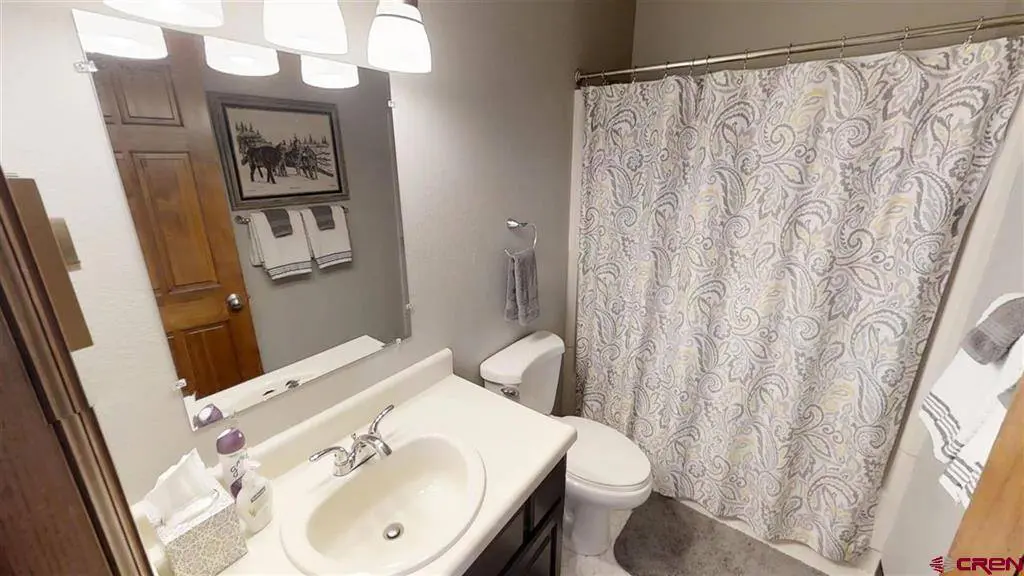 A bathroom with a shower curtain and sink.