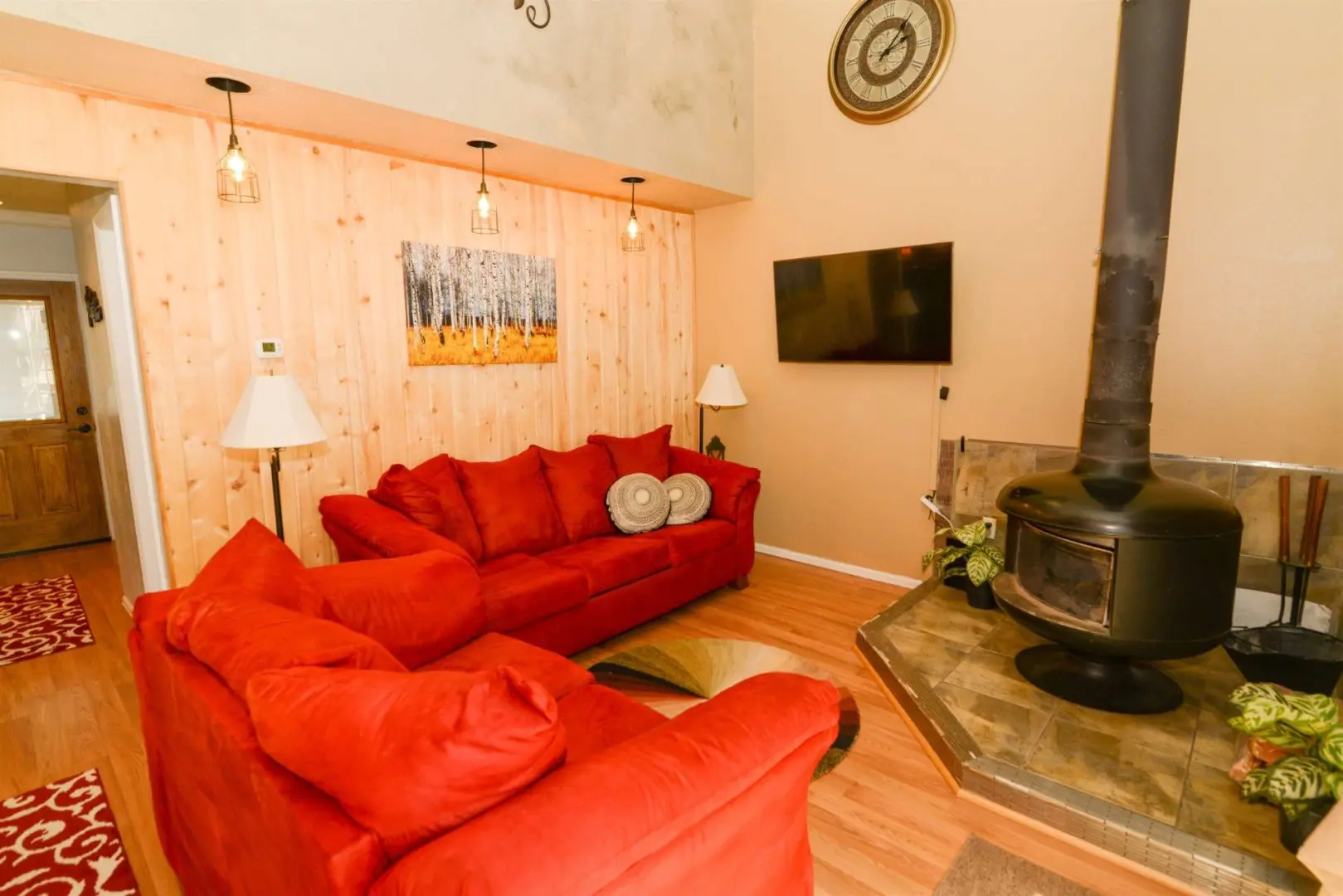 A living room with red couches and a wood burning stove.