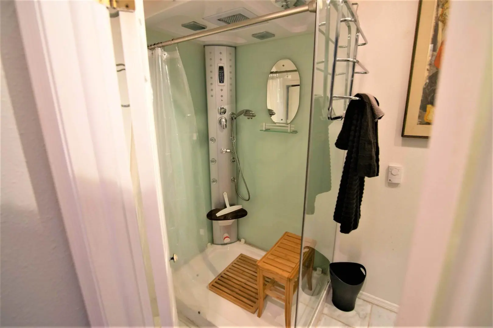 A small bathroom with a shower stall and a stool.