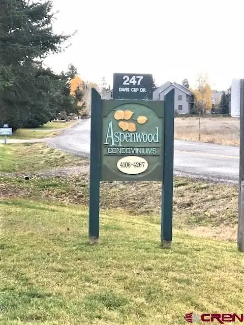 A sign for aspenwood apartments in the middle of a grassy field.