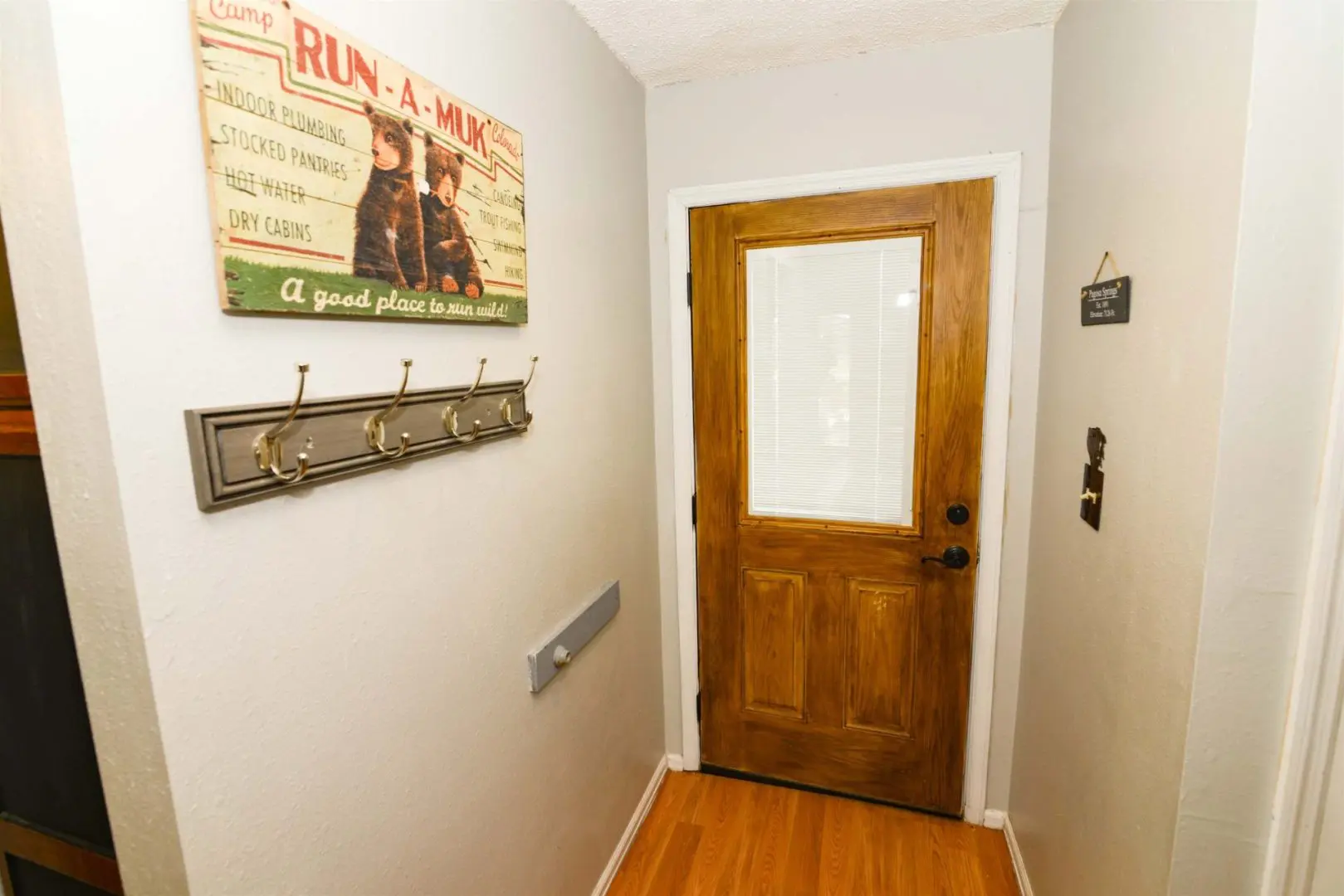 A hallway with a wooden door and hooks on the wall.