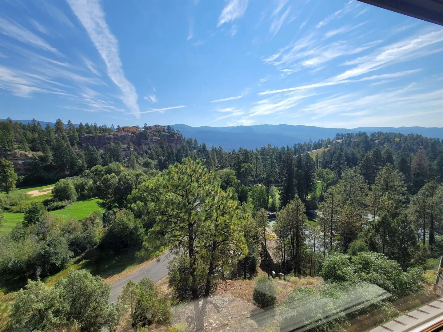 A view of a golf course and mountains from a window.