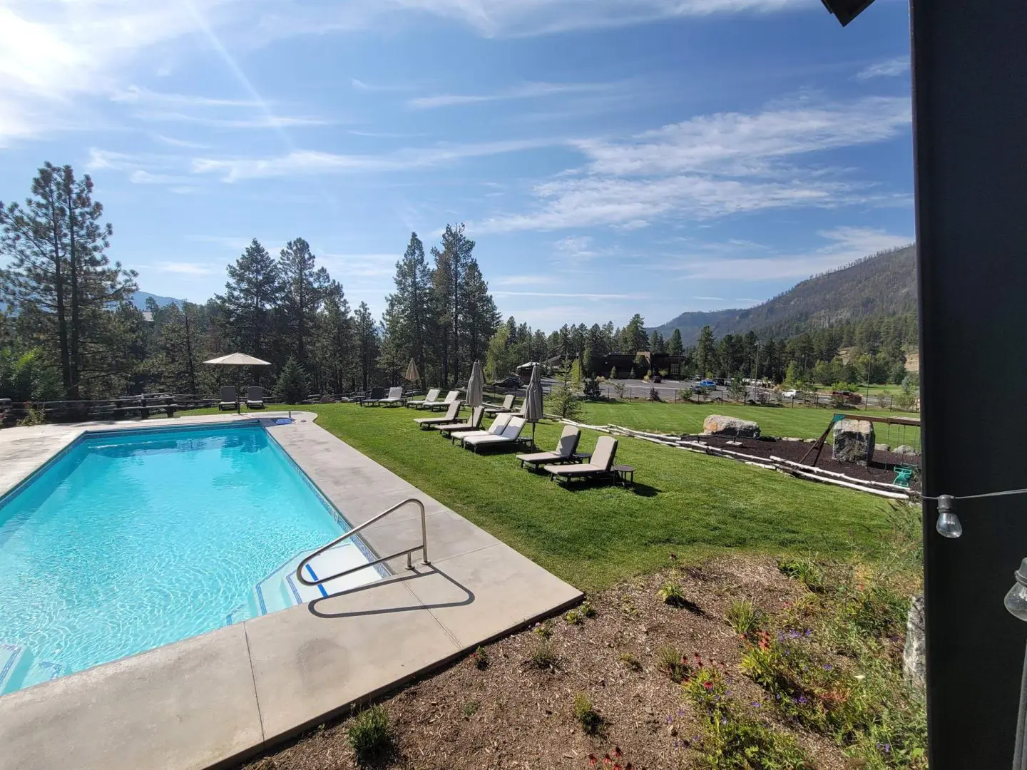 A view of a swimming pool with lounge chairs and mountains in the background.