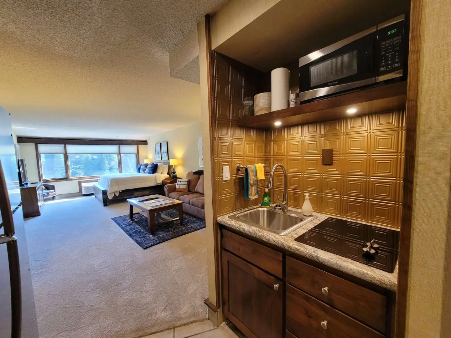 A kitchen in a hotel room with a microwave and refrigerator.