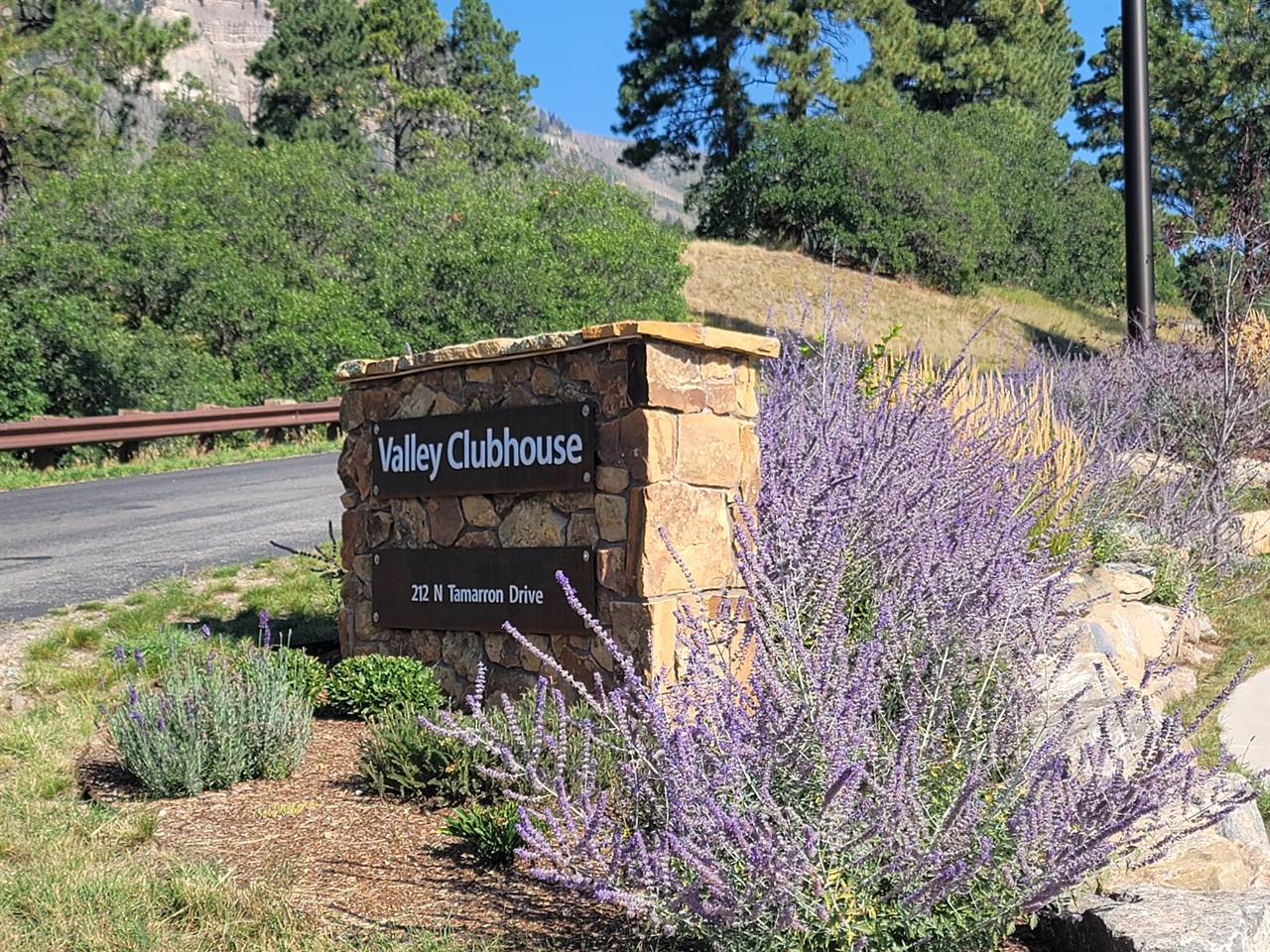 A stone sign with purple flowers in front of it.