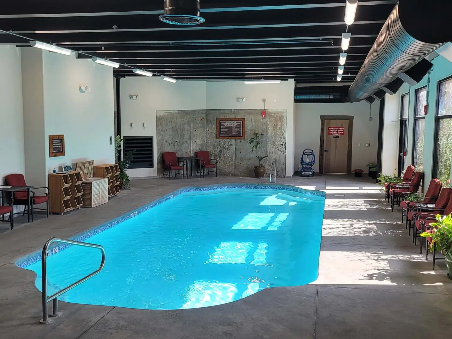 A swimming pool in a room with chairs.