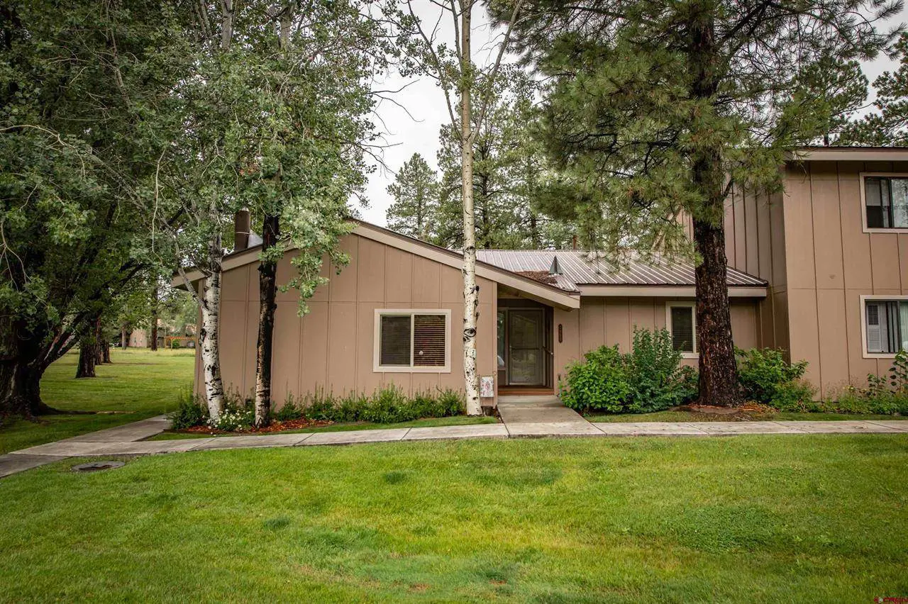 A home with a lawn and trees in front of it.