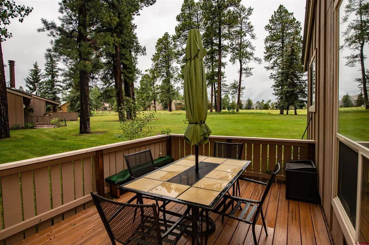 A deck with a table and chairs overlooking a golf course.