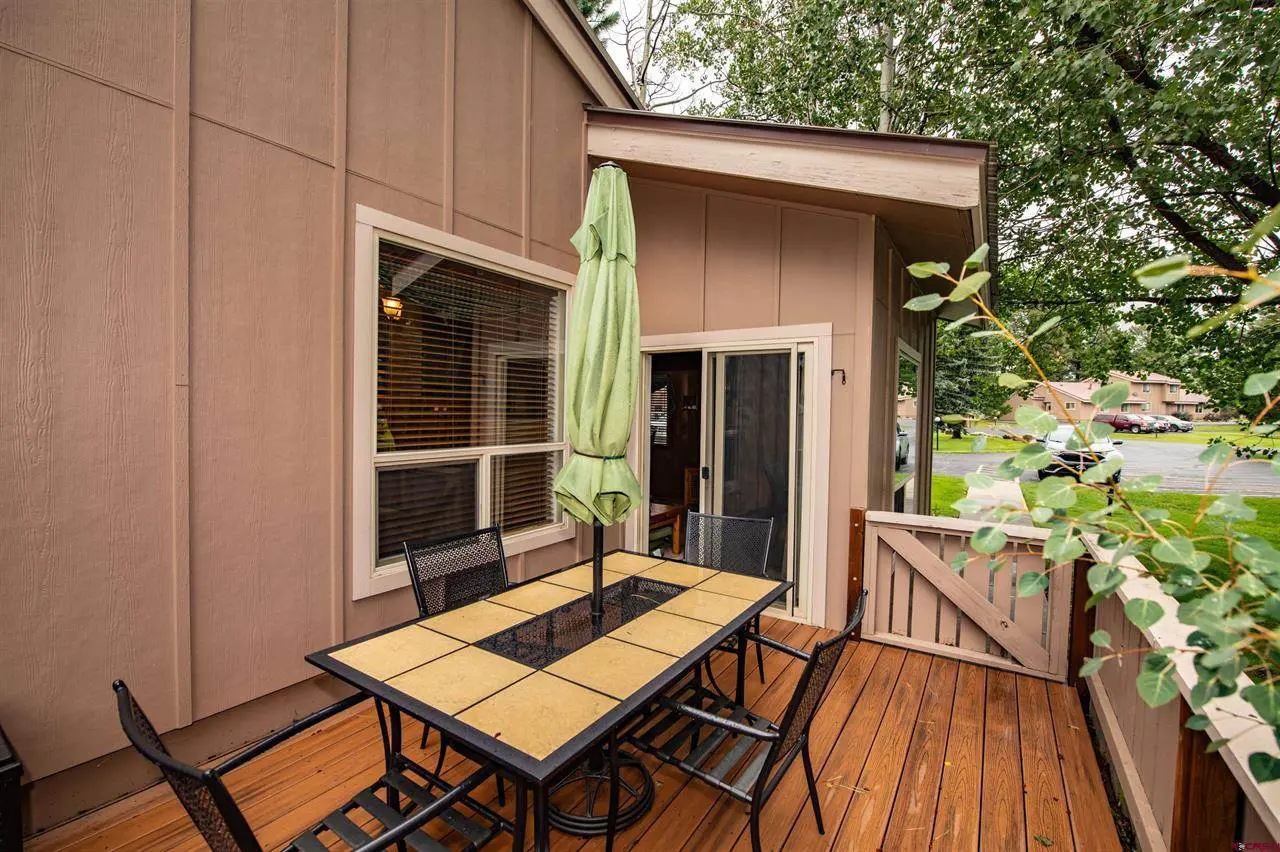 A deck with a table and chairs and an umbrella.