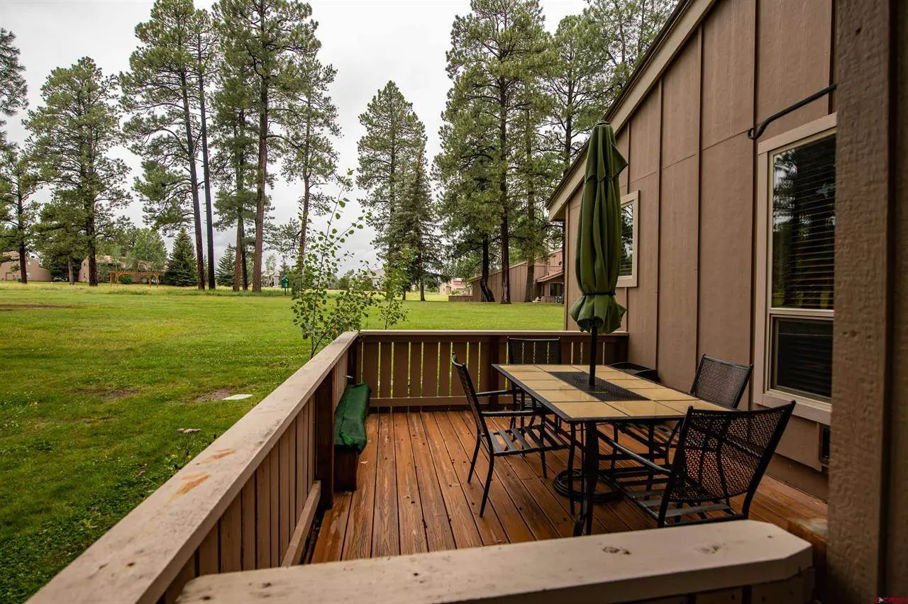 A deck with a table and chairs overlooking a wooded area.