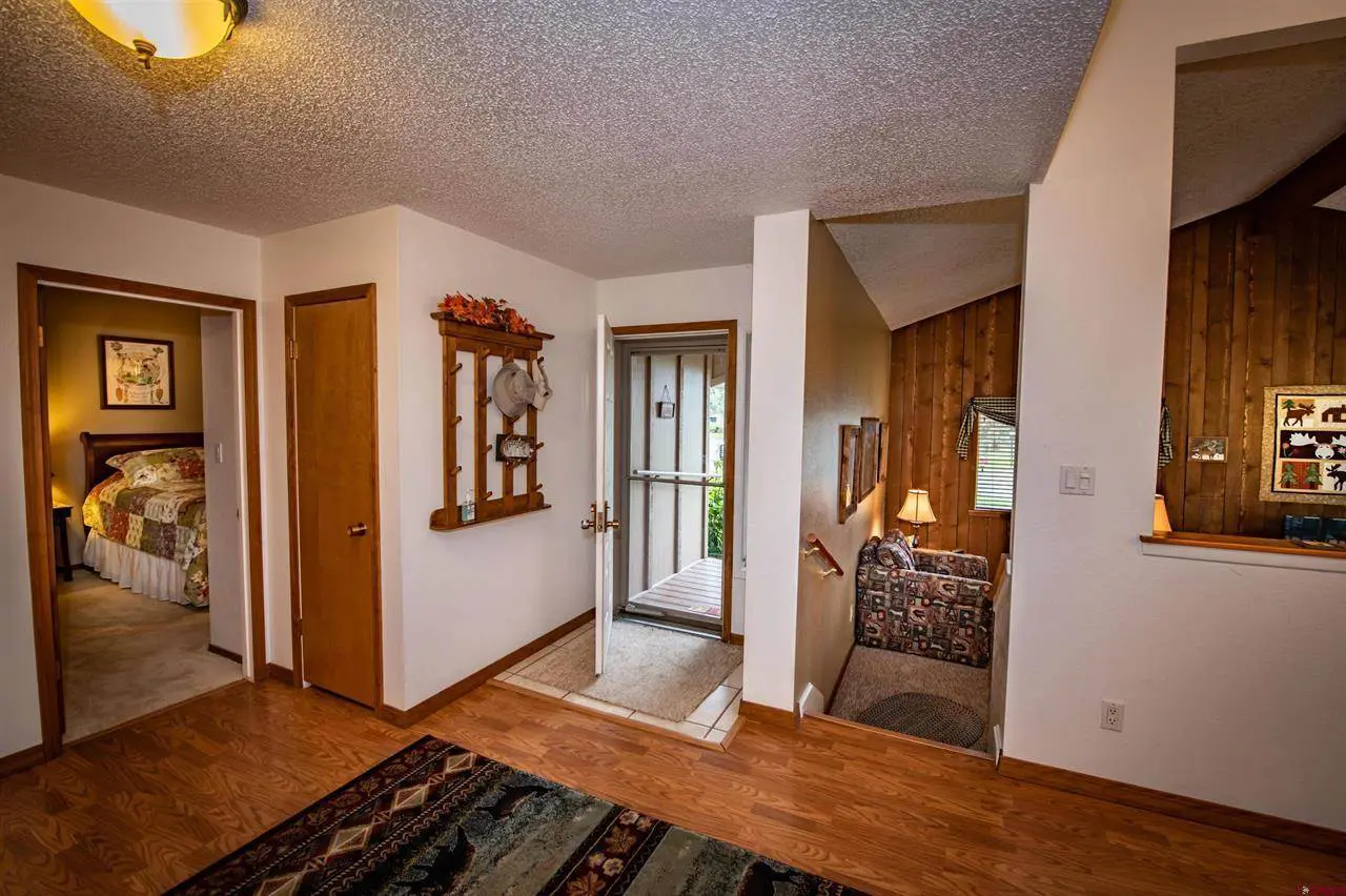 A hallway with hardwood floors and a door leading to a bedroom.