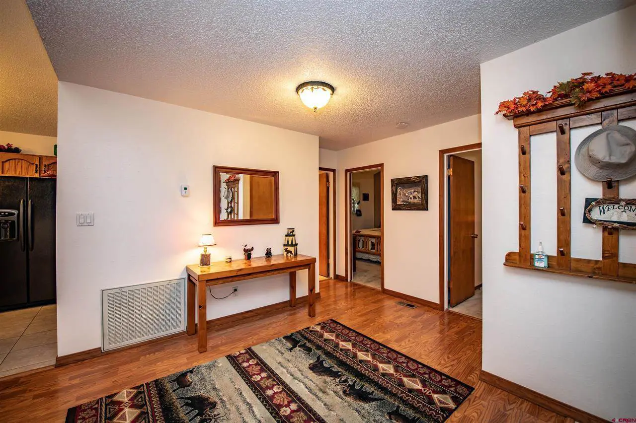 A hallway with hardwood floors and a rug.